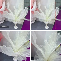 Grande fleur géante en tissu organza blanc, sur pied, pour la décoration d'allées de mariage et de scènes.