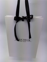 Sac cadeau artisanal en papier biodégradable éco-responsable minimaliste avec logo personnalisé et nœud en ruban satiné noir pour boutique de mode et magasin de chapeaux