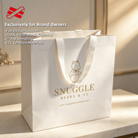 Sac en papier ivoire OEM avec poignée en ruban tissé et logo ours en feuille d'or pour la vente au détail en crèches, faible MOQ
