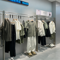 Boutiquede vêtements d'affairesélégants avecaffichage en métalnoir, cintres linéaires et unités de rangement à plusieurs niveaux