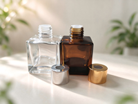 Flacon diffuseur de parfum carré de luxe de 50 ml, disponible en transparent et ambre, avec bouchons et bouchons intérieurs dorés et argentés.