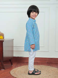 Lindo niño pequeño con kurta azul estampada y pijama blanco, sonriendo mientras se encuentra en el interior de una casa, con un atuendo étnico tradicional indio. - Product Image 3