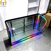 Comptoir d'exposition moderne éclairé par LED RGB avec piliers noirs et étagères en verre multi-niveaux pour magasin de vente de produits fumeurs