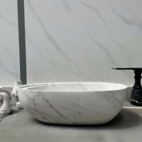 Baignoire ovale autoportante en marbre de Carrare italien avec rebord épais et arrondi et siège intérieur profilé pour projet de salle de bain de penthouse