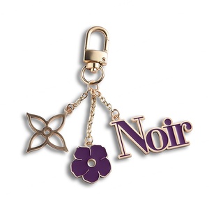 Porte-clés mini sac à main en métal émaillé souple, motif fleur violette ajourée, avec logo personnalisé - Product Image 1