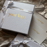 Boîte cadeau rigide de luxe avec papier texturé gaufré, logo en feuille d'or et ruban en satin pour parfums, cosmétiques et emballages cadeaux