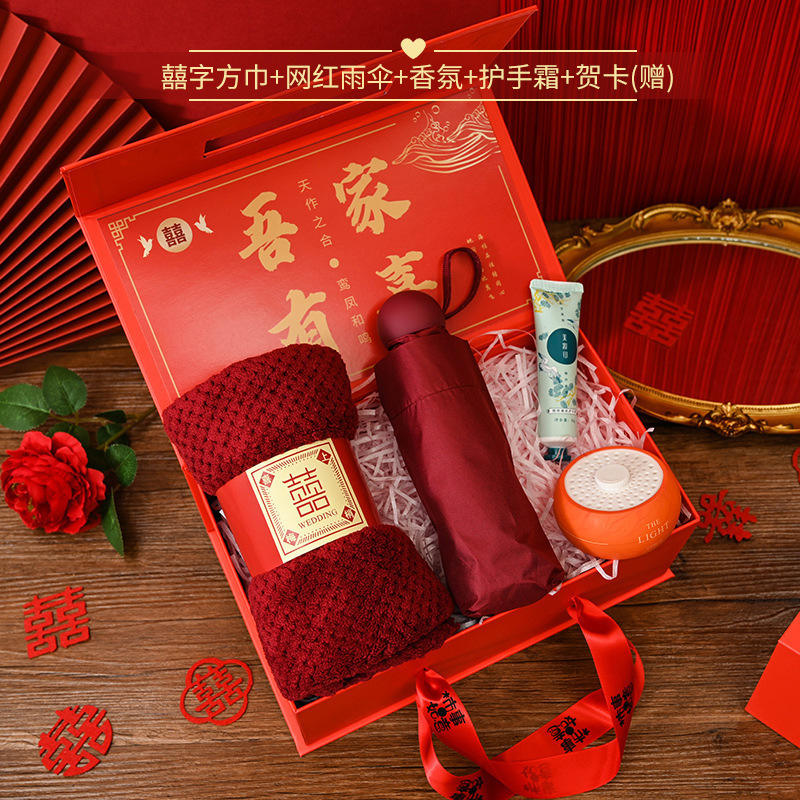 [Ensemble de quatre pièces comprenant un foulard carré avec le symbole du double bonheur, un parapluie populaire et une crème pour les mains aromathérapie] avec une boîte rouge symbolisant la bonne fortune.