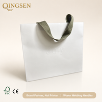 Sacs shopping personnalisés en papier blanc avec logo gaufré, poignées en sangle tissée, finition mate, lot en gros pour boutiques de détail