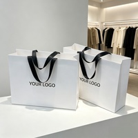 Sacs de courses en papier épais blancs écologiques réutilisables en gros avec logo personnalisé et poignées en ruban de soie noir pour vêtements