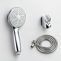 Douche à main chromée avec flexible tressé, support réglable à angle variable et fixation murale sans perçage pour salle de bain d'hôtel