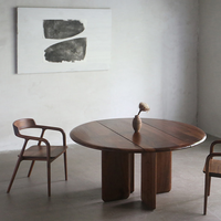 Table à manger ronde en noyer massif de style Mid-Century, avec trois pieds en dalle et piétement croisé, idéale pour studio ou loft