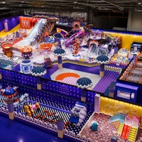Équipement complet de terrain de jeux intérieur, thème Océan, avec toboggan spiralé jaune, piste de train surélevée, manège fusée, trampoline et mousse.