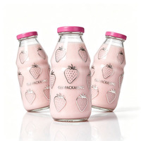 Les marques de boissons bio utilisent des bouteilles de lait en verre transparent ergonomiques et rainurées avec des bouchons à vis en métal rose fuchsia.