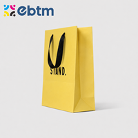 Sacs cadeaux en papier jaune mat personnalisés en gros avec poignées en ruban noir pour sacs cadeaux cosmétiques