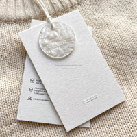 Étiquettes suspendues personnalisées de luxe en papier coton avec bouton coquille et cordon en coton, imprimées en relief pour l'image de marque de vêtements