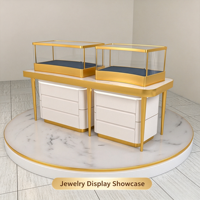 Comptoir de présentation de bijoux compact et combiné, vitrine en verre à cadre fin doré avec base de rangement à tiroirs blancs et plateforme ronde en marbre