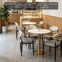 Table ronde en pierre frittée avec structure en métal doré et ensemble de fauteuils en cuir pour café, boulangerie, salon de thé, mobilier commercial