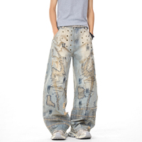 Jean vintage délavé coupe large avec broderie abstraite, œillets métalliques, effet usé et bords effilochés, style streetwear ample