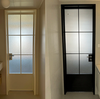 Porte de salle de bain à battants en verre dépoli, cadre en métal noir, poignée à barre, ouverture vers l'intérieur, porte de séparation intérieure moderne pour l'intimité