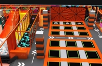 Équipement de parc de trampolines intérieur sur mesure sur le thème de la course automobile avec fosse à mousse, toboggans et parcours d'obstacles