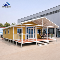 Villa modulaire préfabriquée avec toit à pignon, véranda avant, terrasse et balustrade pour la vie en plein air, maison-conteneur moderne