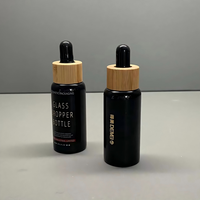Vente en gros de flacons compte-gouttes en verre noir brillant de 30 ml avec compte-gouttes en bambou et impression sérigraphique pour les gouttes pour les yeux et les sérums pour le soin de la peau