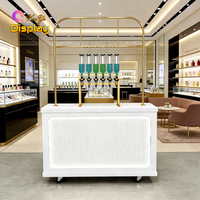Bar à parfums de luxe moderne avec distributeurs en verre suspendus à cadre métallique doré, dotés d'un design LED écologique pour les magasins de détail haut de gamme