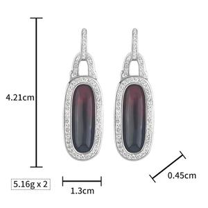 Estos pendientes presentan un marco ovalado de resina con incrustaciones de circonitas cúbicas que combinan un diseño moderno con un brillo clásico. - Product Image 2