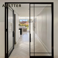 Porte battante AOSTTER noire en aluminium mince avec vitrage transparent pleine hauteur et charnière dissimulée pour un intérieur minimaliste