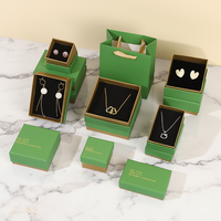 Série d'emballages de bijoux sophistiqués A1 avec couvercles de boîtes vert et blanc, couches de base marron et noires, texte personnalisé et sac de transport