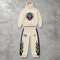 Ensemble deux pièces personnalisé pour homme : sweat à capuche crème avec motif tête de mort et pantalon de jogging à cordon de serrage avec empiècements latéraux flamme noire OEM ODM