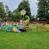 Manège pliable géant Caterpillar vert sur remorque, équipement d'amusement portable, idéal pour les fêtes foraines nomades.
