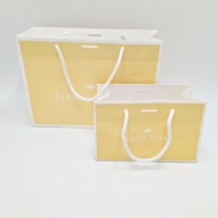 Bolsa de regalo de papel laminado al por mayor con asa de cinta y logotipo impreso personalizado para embalaje de joyería, ropa y calzado.