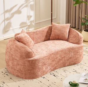 Canapé compressible rose incurvé pour deux personnes. Il possède des accoudoirs des deux côtés et est livré avec deux oreillers. - Product Image 1