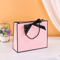 Vente en gros de sacs à provisions en carton rose de luxe poignées sac en papier de luxe logo personnalisé pour vêtements sac en papier de luxe ruban pour l'artisanat