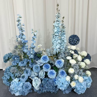 Vente en gros pour mariage : Composition florale de 70 cm pour allée de mariage, avec rangée de fleurs en soie bleues, champagne et rouges, et roses blanches