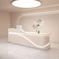 Vente en gros de comptoirs de réception personnalisés, modernes, minimalistes, blancs, avec un design ondulé, éclairés par LED, pour salons de beauté, spas capillaires, cliniques, bureaux