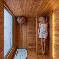 Sauna extérieur moderne en forme de cube, préfabriqué en bois massif, avec grande fenêtre panoramique en verre pour villa, jardin ou spa.