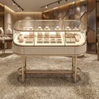 Table de présentation de bijoux ovale à texture côtelée, cadre or champagne, vitrine à bijoux en verre incurvé, comptoir de présentation de bijoux avec éclairage LED