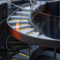 Escalier intérieur courbé de luxe avec poutres en acier courbées, marches en marbre et garde-corps en verre