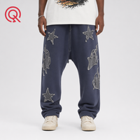 Jogger homme Y2K personnalisé en usine, bleu marine légèrement délavé, avec patch étoile appliqué effet usé et coupe entrejambe basse, à revers.