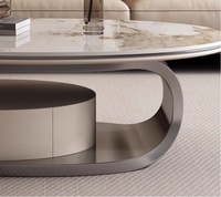 Table basse ovale moderne avec dessus en pierre frittée, pieds en métal beige, imbriqués et extensibles, pour salons confortables