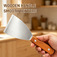 Ensemble d'ustensiles de cuisine en acier inoxydable gris avec manche en bois : spatule, pelle, poêle à frire, plaque à pizza et plaque de cuisson anti-goutte