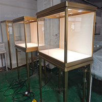 Vitrine de présentation sur pied avec plateau en verre carré, éclairage LED intégré, pour bijouterie, horlogerie et exposition en galerie.