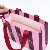 Sac cadeau en papier rayé rose et bordeaux personnalisé avec poignée en ruban de satin et logo imprimé en feuille d'or pour emballage de beauté haut de gamme