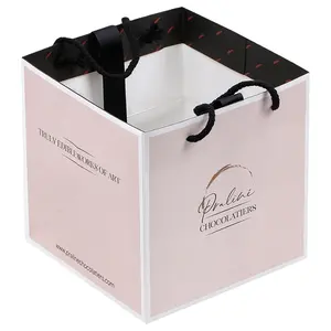 Sacchetto di carta regalo con logo personalizzato di marca di lusso per vestiti sacchetti di imballaggio boutique di abbigliamento opaco rosa con manici a nastro