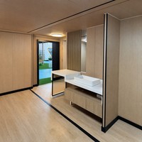 Maison conteneur durable et extensible de 20 pieds avec toit à pignon, cadre noir anthracite, fenêtres en treillis, terrasse isolée pour lodge rural