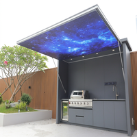 Cuisine extérieure moderne tout-en-un en acier inoxydable avec îlot barbecue, réfrigérateur, évier, rangement et éclairage de plafond