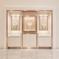 Présentoir mural pour montres et bijoux blanc crème, cadre or rose, niches murales cannelées, vitrines en verre, armoire de rangement et éclairage LED