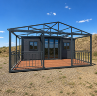 Maison conteneur pliable extensible gris foncé avec terrasse en bois, garde-corps métallique et toit à pignon pour le glamping sur terrain aride